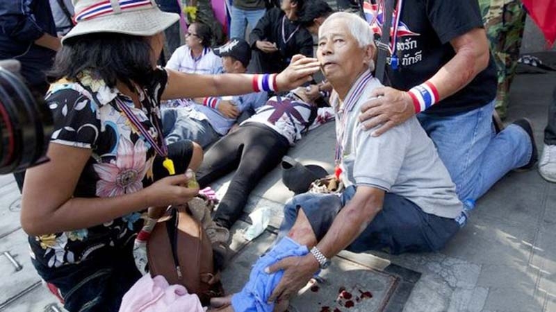 A man injured by an explosion is helped after an explosive device went off during an anti-government protest march in Bangkok on Friday.